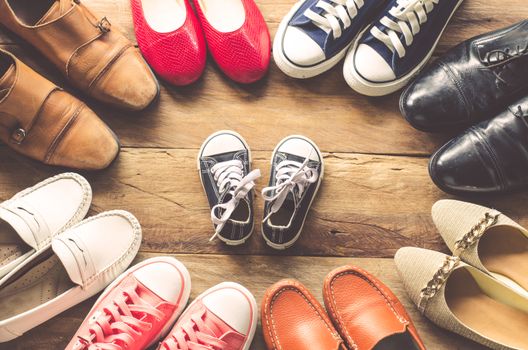 shoes various styles with children's shoes in the middle on a wooden floor - the concept of family care.