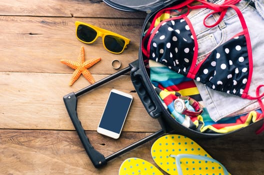 Clothing traveler's , wallet, smart phone devices, on a wooden floor in the luggage ready to travel.