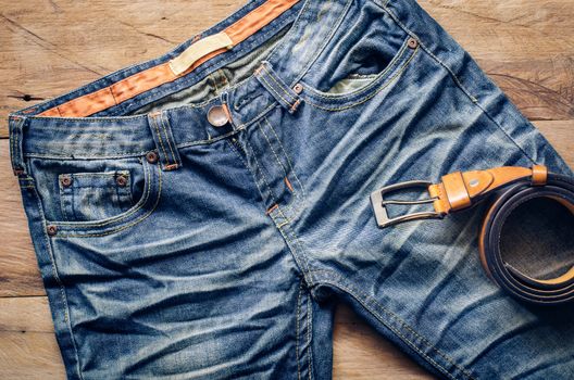 blue jeans with leather belt on wooden background 