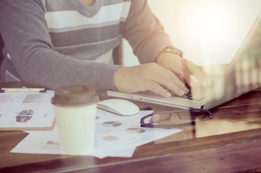 Businessman holding paperwork on the table and analyzing investment chart working in office. Business work concept.