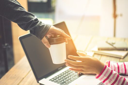 Close up-team businessman giving a cup of coffee to female in creative office.