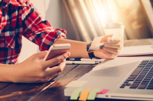 Woman holding credit cards and mobile phones is shopping over the internet by paying by credit card.