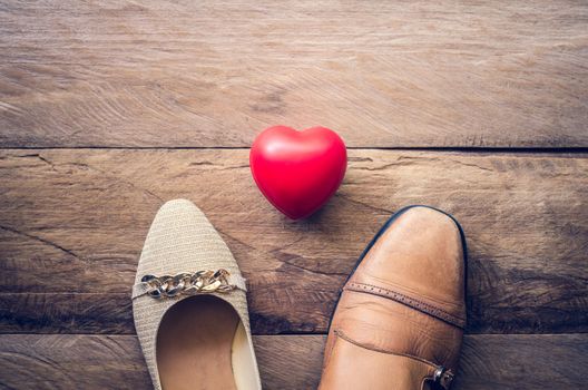 Women's shoes and men's shoes with hearts placed on a wooden floor with the concept of love.