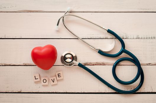 stethoscope heart and the word "love"on wooden floor