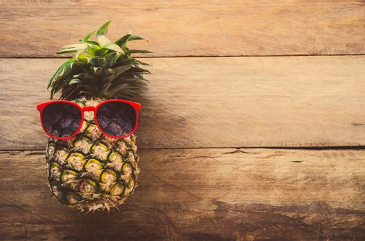 Pineapple sunglasses resting on the wooden floor concept travel.