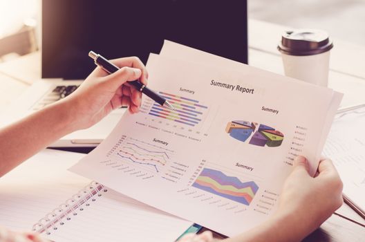Businessman holding paperwork on the table and analyzing investment chart working in office. Business work concept