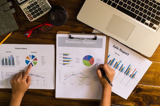 Businessman holding paperwork on the table and analyzing investment chart working in office. Business work concept. 