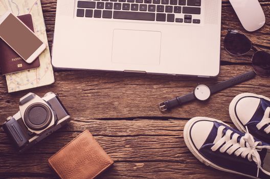 Laptop and travel accessories costumes.Tourism planning and equipment needed for the trip on wooden floor