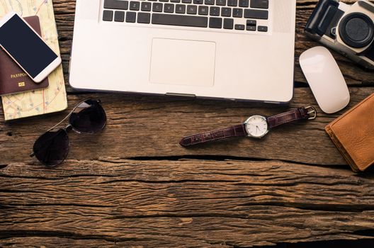Laptop and travel accessories costumes.Tourism planning and equipment needed for the trip on wooden floor