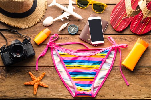 Beauty colorful bikini and accessories on wooden floor for trip on summer 