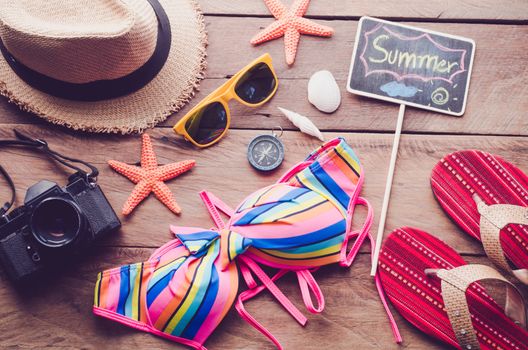 Sea travel accessories colorful bikini and accessories sandals. Placed on wooden and word 'SUMMER" on blackboard