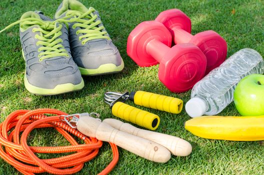fitness concept with Exercise Equipment on green grass background.