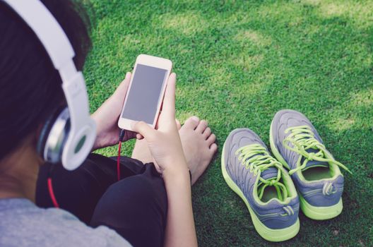 Teenage is listen song and hand hold smart phone on green grass floor 