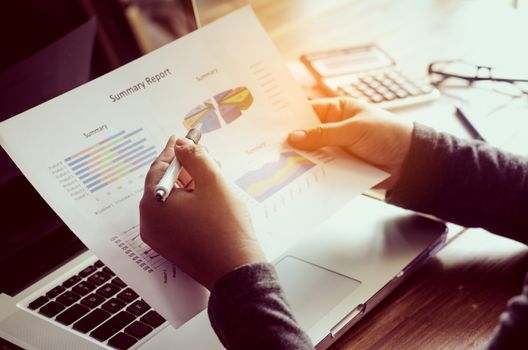 Businessman holding paperwork on the table and analyzing investment chart working in office. Business work concept. 