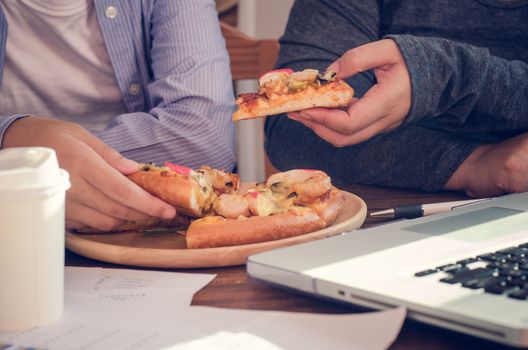 Business team is eating pizza at work while working
