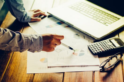 Businessman holding paperwork on the table and analyzing investment chart working in office. Business work concept. 