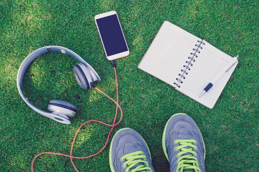 Relaxing concept with music listening device on green grass