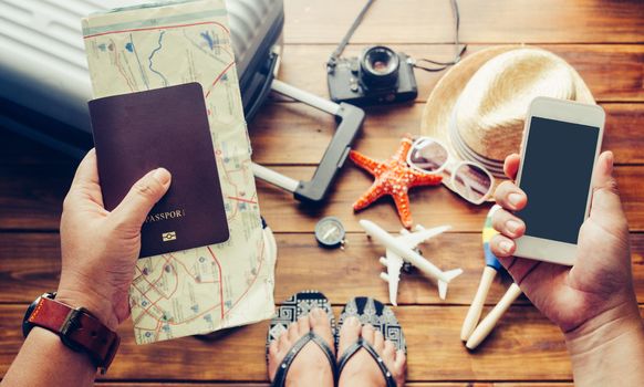 Traveler holds passport and smart phone with luggage, costume, camera in the floor background. Along with travel