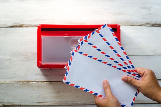 Hands are picking up the envelope in the mailbox.