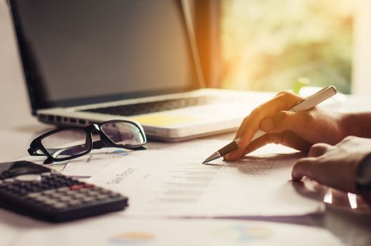 Businessman holding paperwork on the table and analyzing investment chart working in office. Business work concept. 