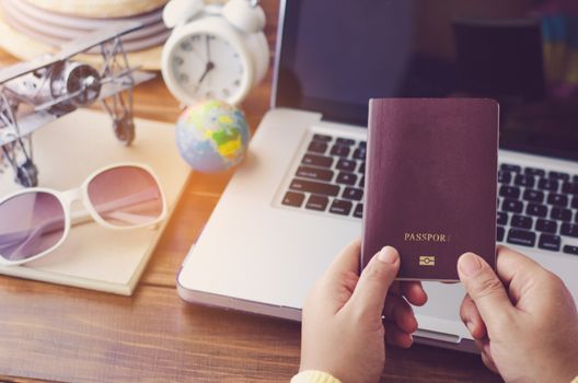 Travelers hold a passport are planning a trip for the holidays on laptop background - concept prepare to travel 