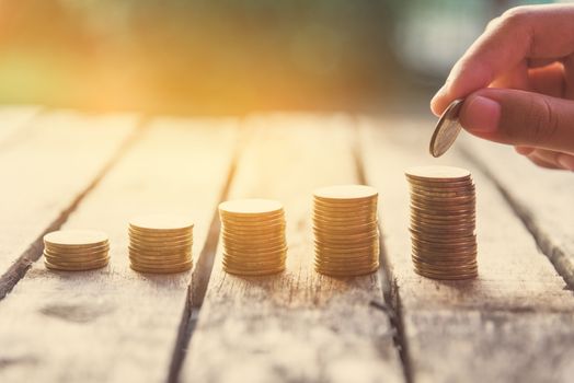 Hand putting money coin on each line rising - business saving money concept. 