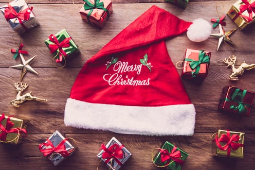 Top view for santa hat with gift boxes on wooden table.