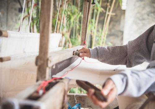 The hand of a weaver is woven with a hand-woven machine.