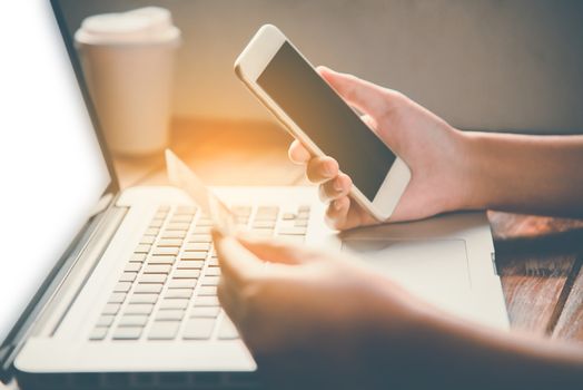 Businessman using credit card and smartphone with a laptop to purchase online