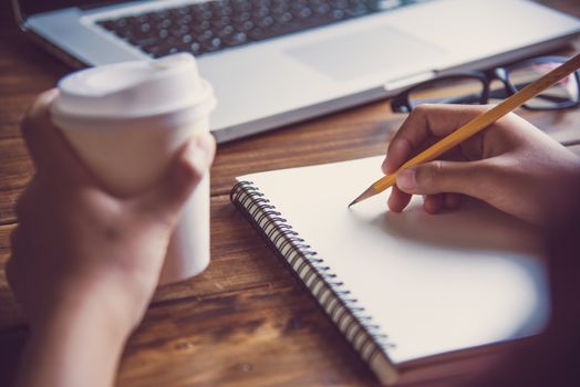 Businessman work on desks, hold a cup of coffee, and have a laptop in the office.