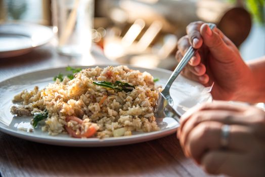 Hand is eating rice fried breakfast.