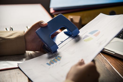People holding a paper punch with for document file