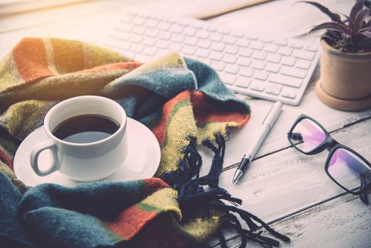 Coffee cup and scarf is placed on a white wooden floor.