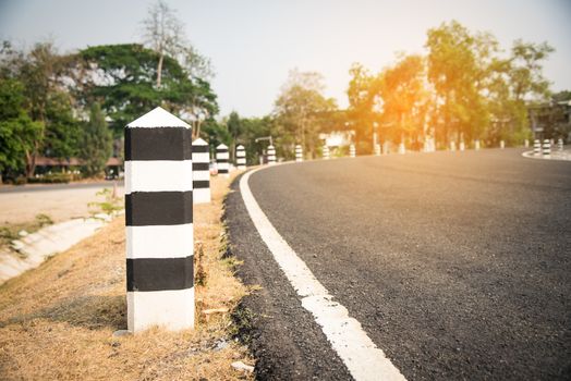 The road with white lines is a dividing line and has black-and-white poles along the way.