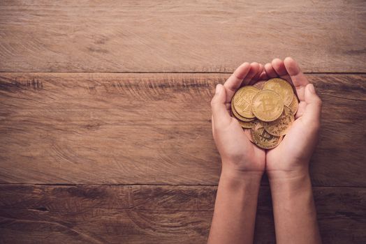 Hands giving gold coin on wooden floor - Concept help for business