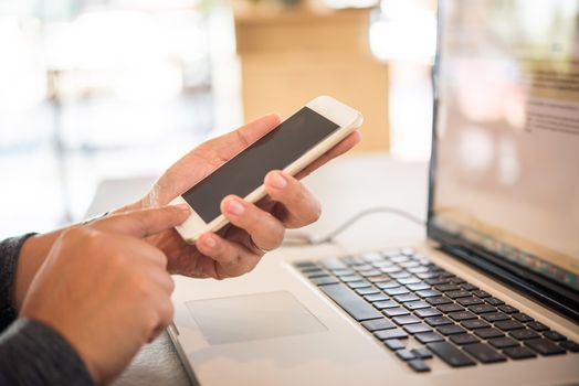 Businessmen use smartphones and laptop to connect and find information in office