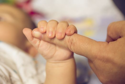 The hands of the mother  hold the baby's hand with love and caring.