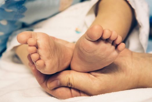 The hands of the mother  hold the baby's feet with love and caring.