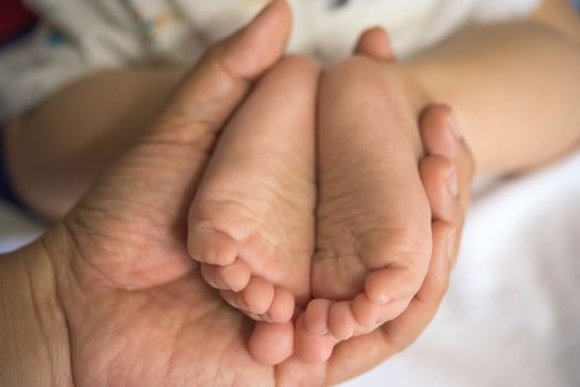 The hands of the mother  hold the baby's feet with love and caring.