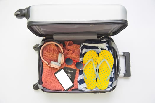 Clothing traveler's Passport, wallet, glasses, smart phone devices, in the luggage ready to travel.