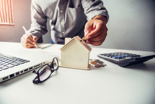  Hand business putting money coin  with wooden house,Property investment and house mortgage financial concept