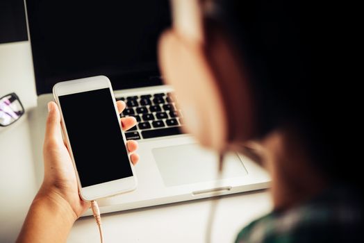  People are using a smartphone to listen to music and wear headphones.