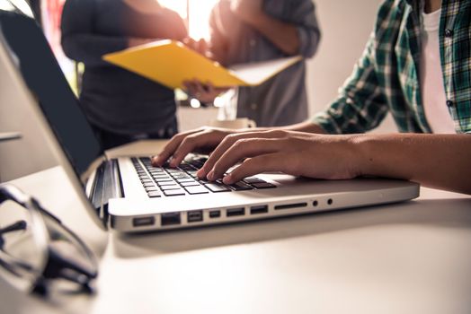 Business people work together to analyze problems, discuss business approaches with smartphone laptops, and office documents in sun glare effect