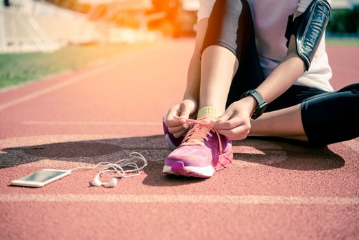 Hands of a young woman shoelace and pink sneakers on a jogging track in the morning to exercise