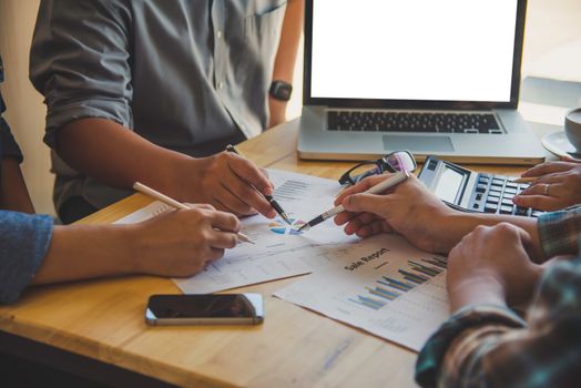 Business people work together to analyze problems, discuss business approaches with smartphone laptops, and office documents in sun glare effect