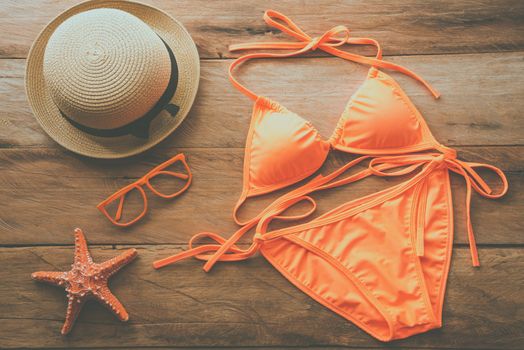 Beauty orange bikini and accessories on wooden floor for trip on summer 