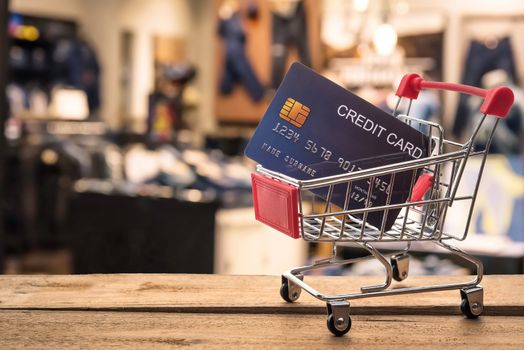 Small shopping cart with credit card inside and behind is blurred. Shop - concept use credit for shopping.