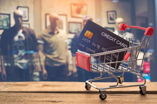 Small shopping cart with credit card inside and behind is blurred. Shop - concept use credit for shopping.