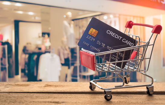 Small shopping cart with credit card inside and behind is blurred. Shop - concept use credit for shopping.
