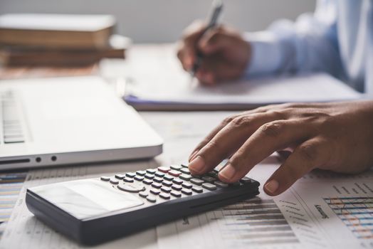 people are working with a calculator and laptop. in office business concept